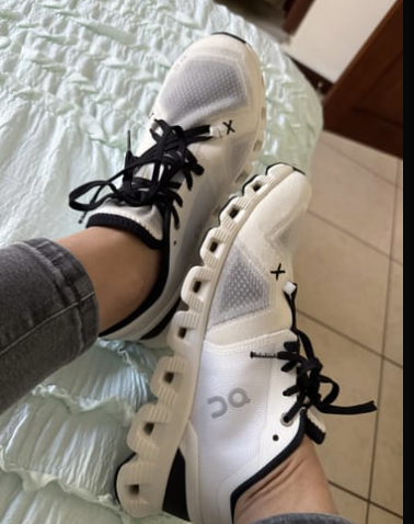 Cliente usando On Cloud X blancos y negros sentada en la cama