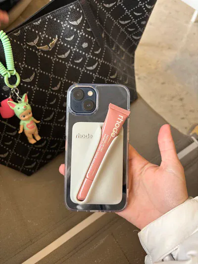 Snap-On Lip Case Rhode rosa adherido a iPhone, sostenido en la mano