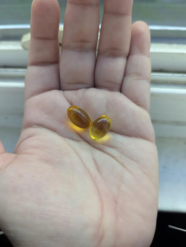 Dos cápsulas blandas de aceite de orégano en la palma de la mano