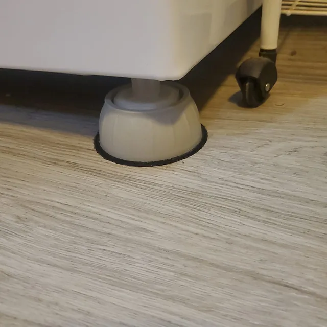 Soporte antivibración instalado bajo lavadora, junto a una rueda